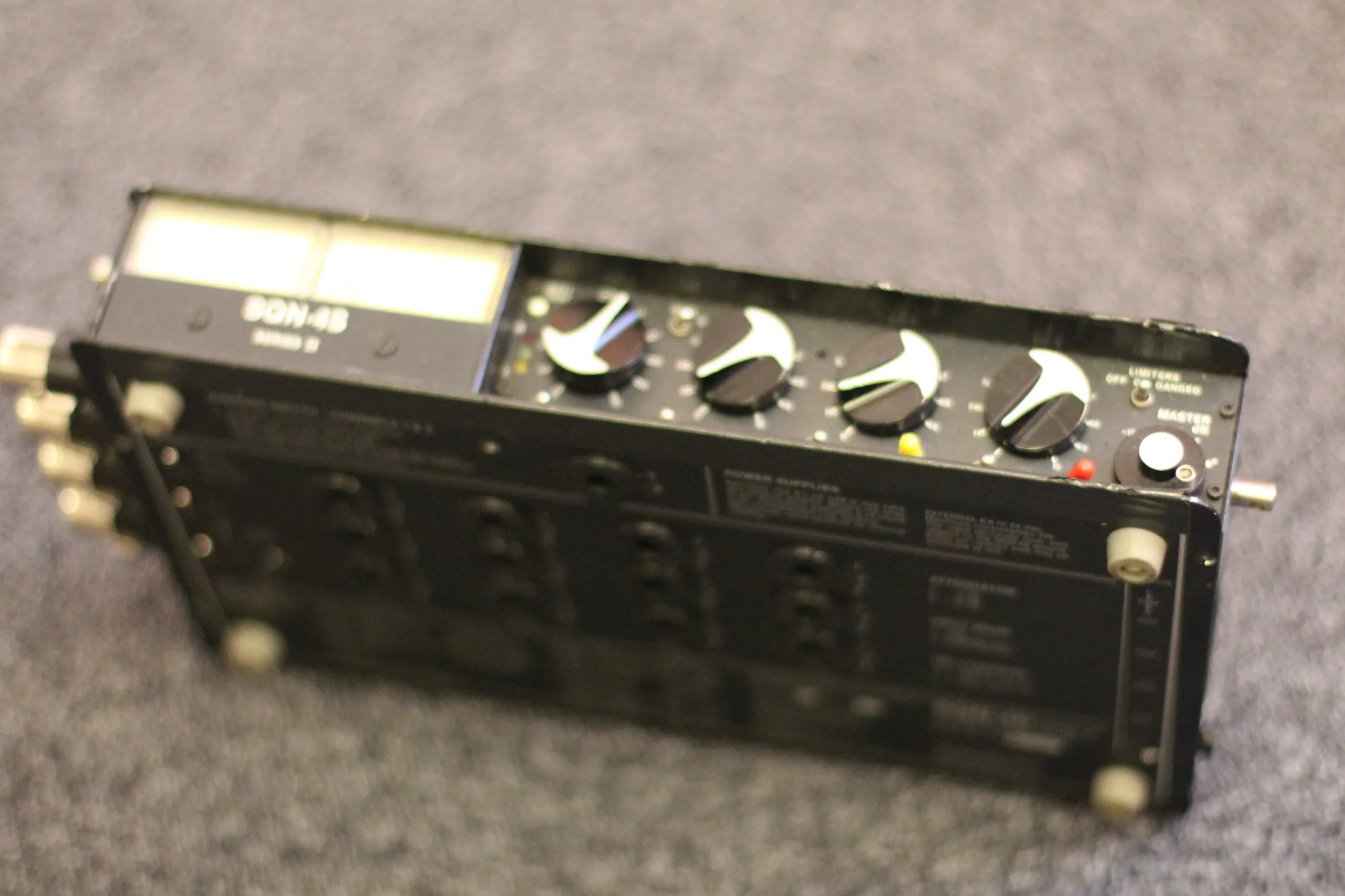 A sound mixer with various knobs and buttons, used to adjust audio levels in a recording studio.