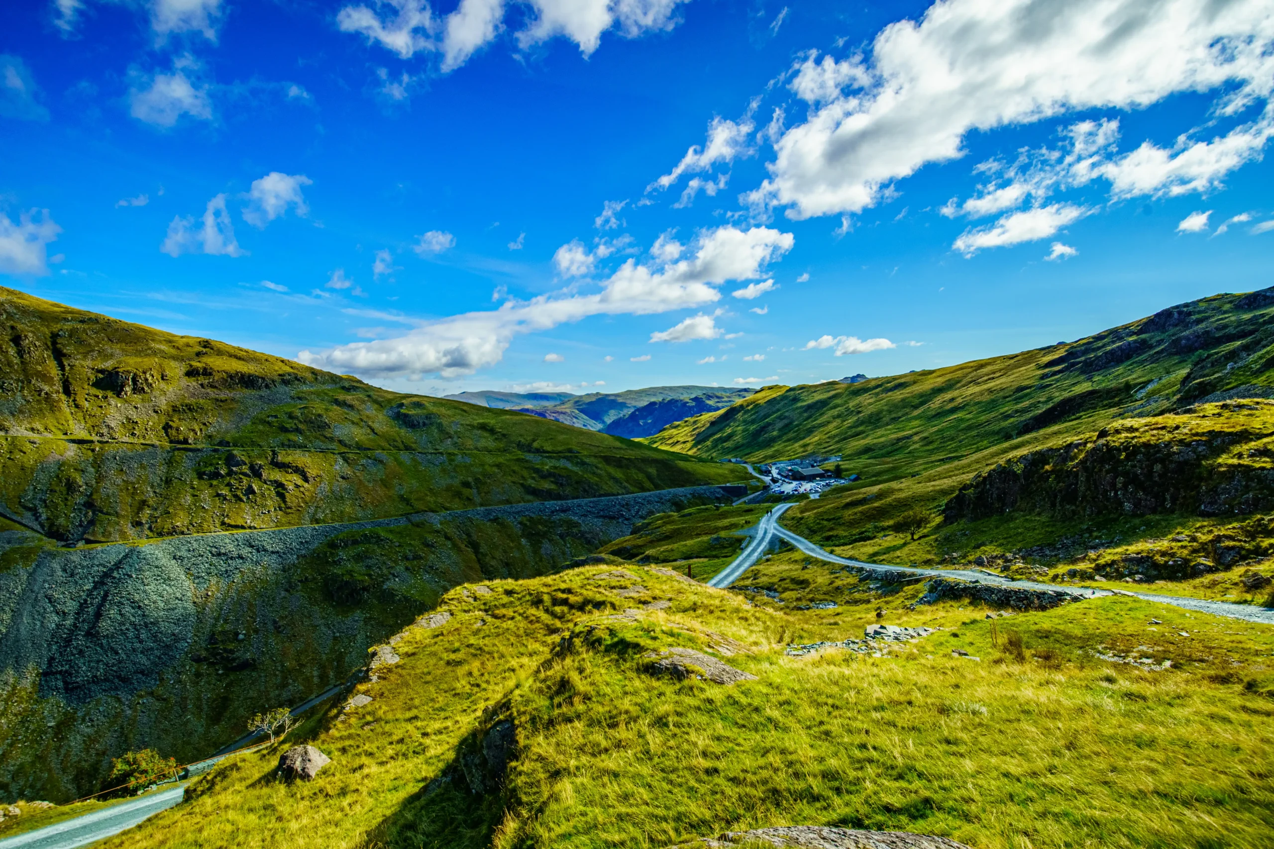 A scenic road winds through the majestic mountains of the Lake District. Nature's beauty at its finest.