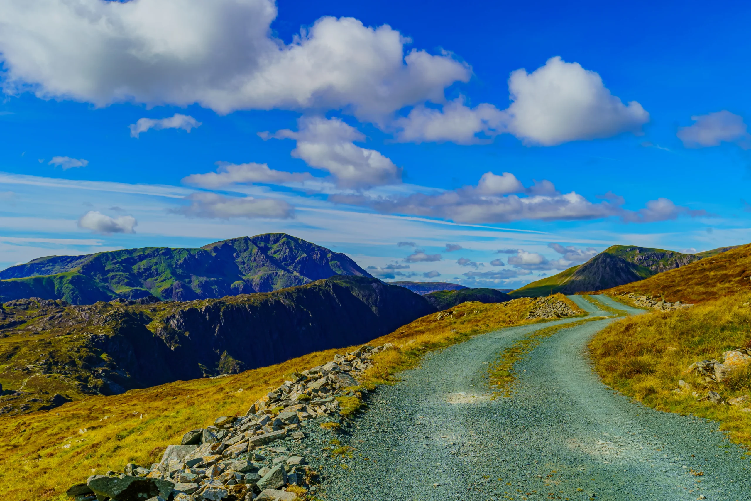 A scenic winding road meanders through lush green hills, creating a picturesque landscape.