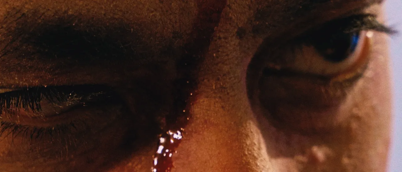 Intense close up of soldier's eye with blood, showing bravery.