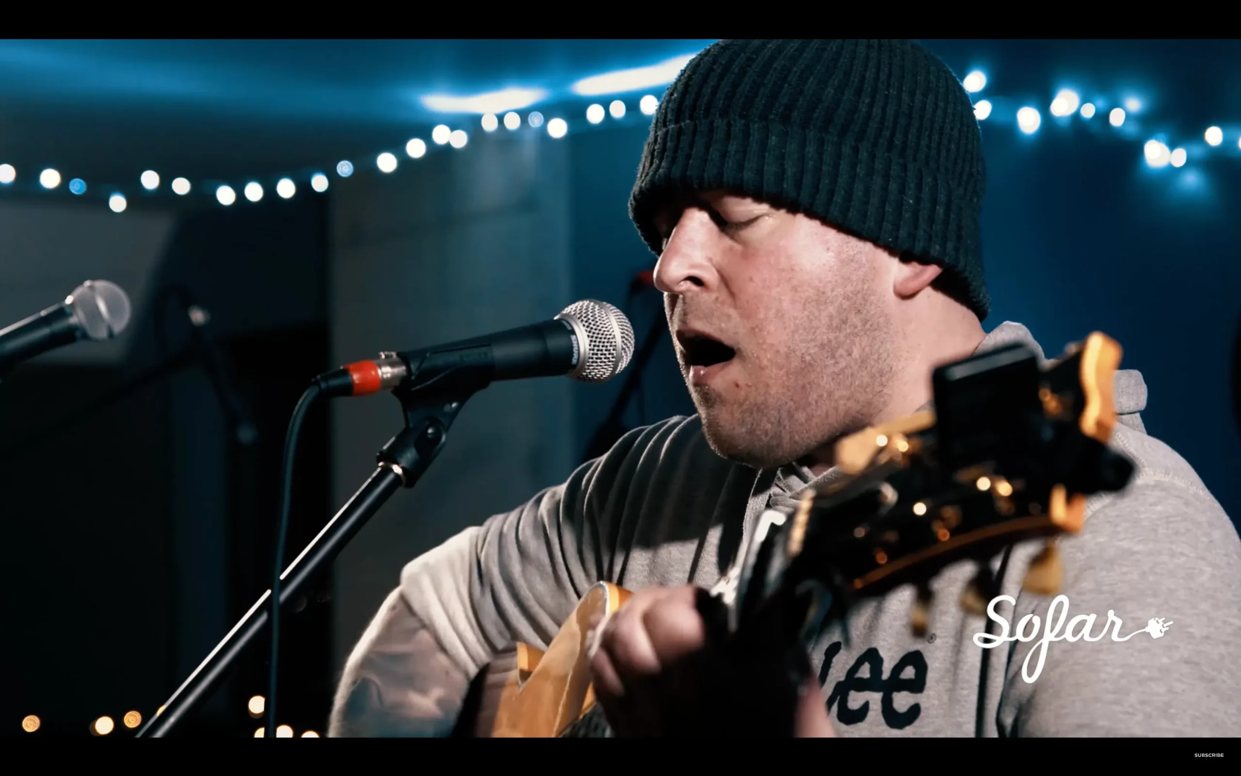 Alex playing guitar and singing passionately on stage, captivating the audience with their musical talent.