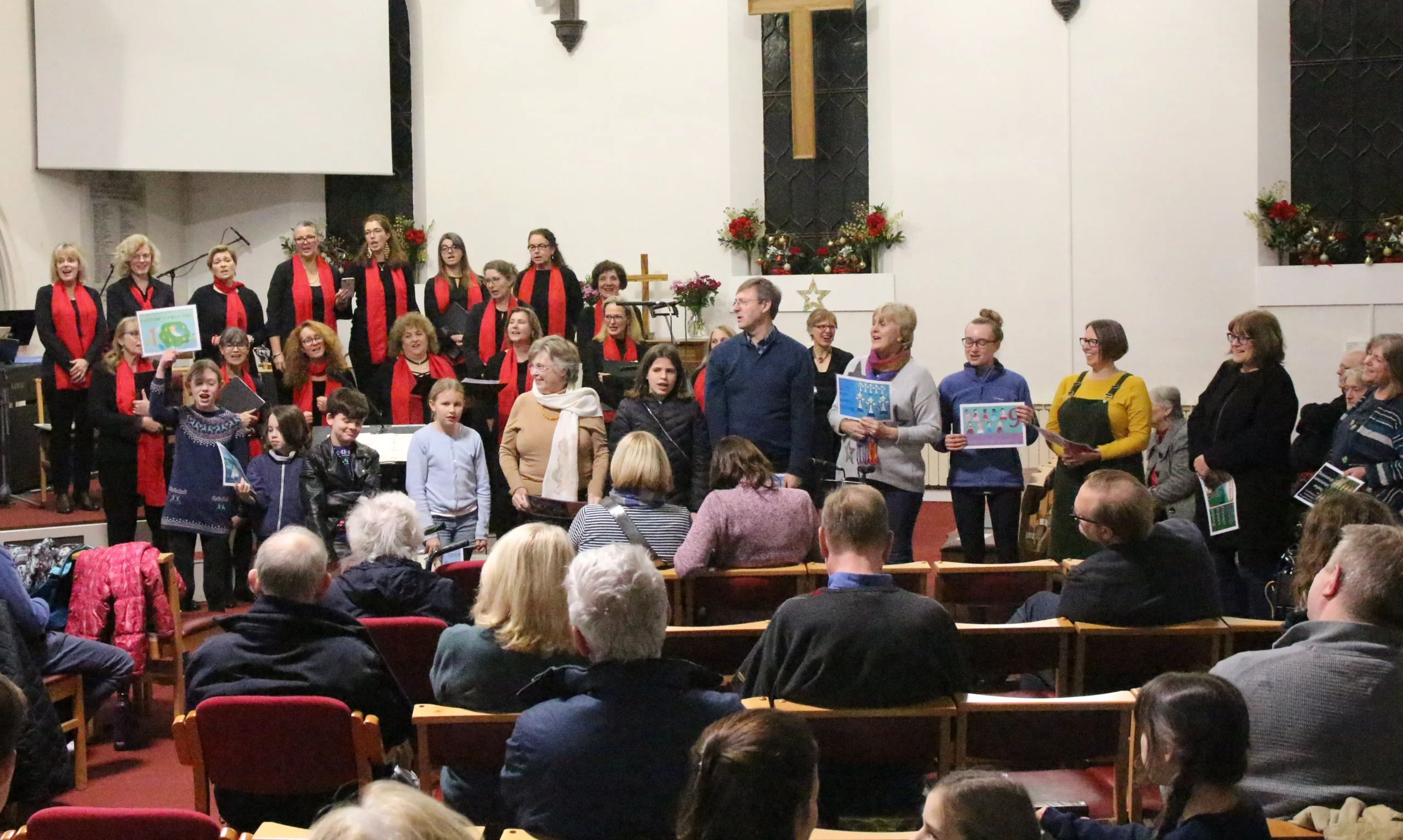 A diverse group of people in a church, with a choir and audience singing joyfully together.