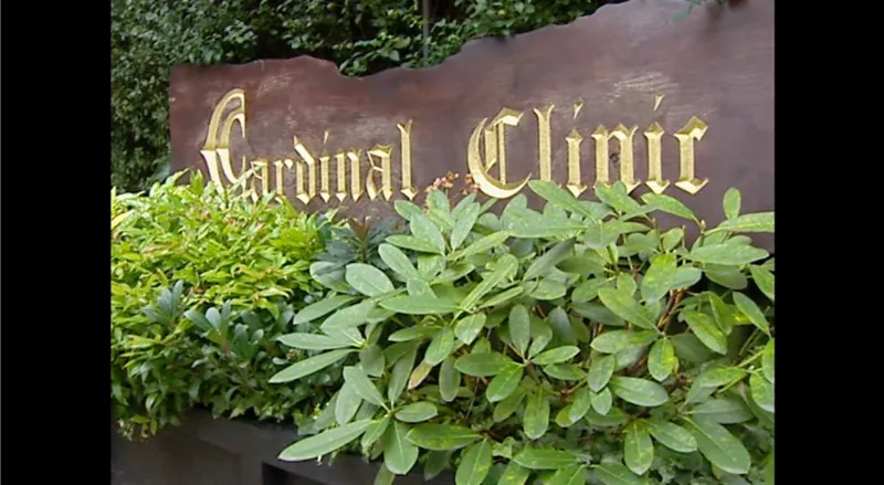 A sign with the words cardinal clinic on behind a hedge