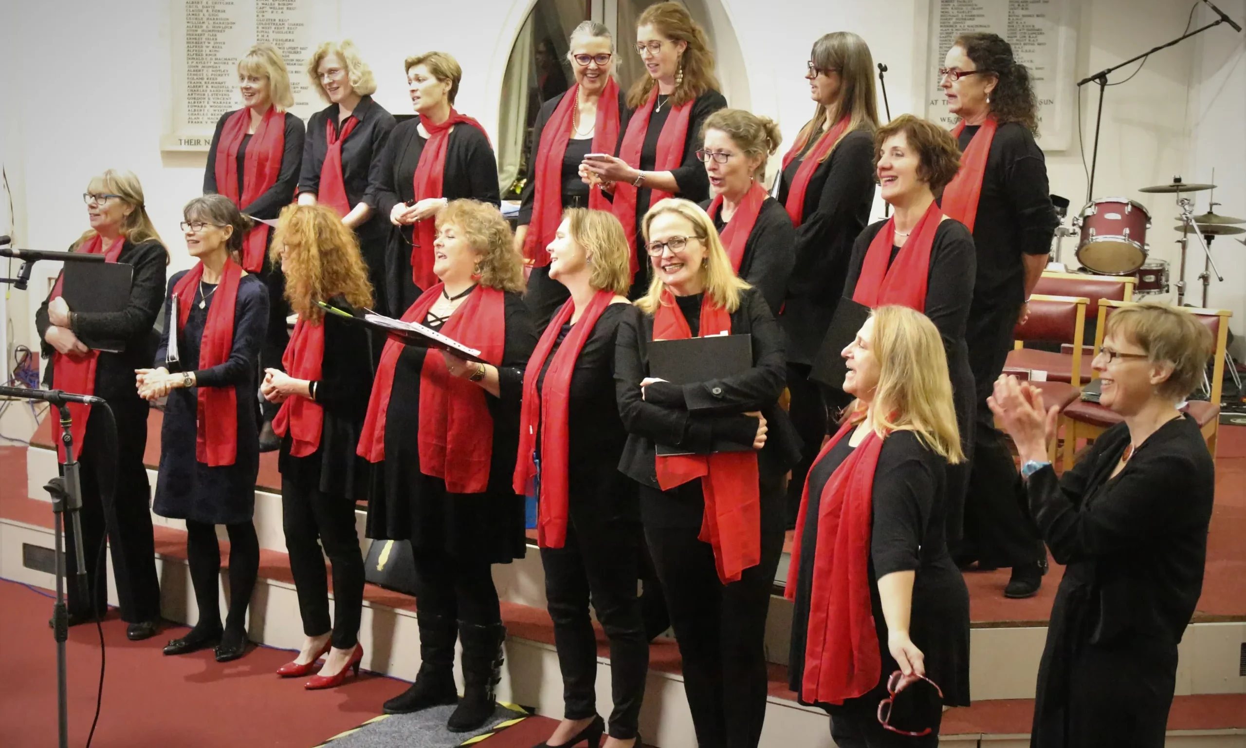 A choir of women in red scarves singing, joyfully captivating the audience with their harmonious voices. #ChoirCheering